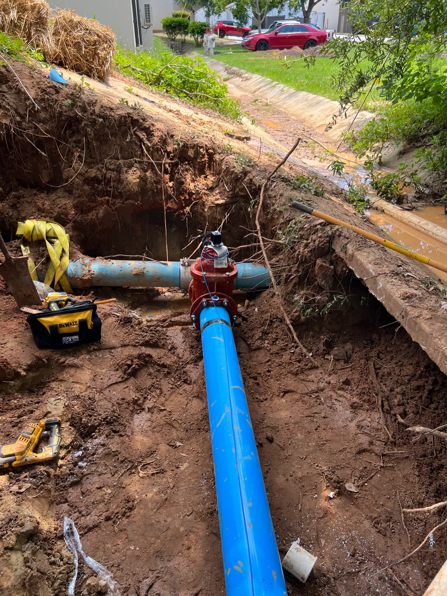 New blue water main tied into an existing line with a red gate valve in an excavation