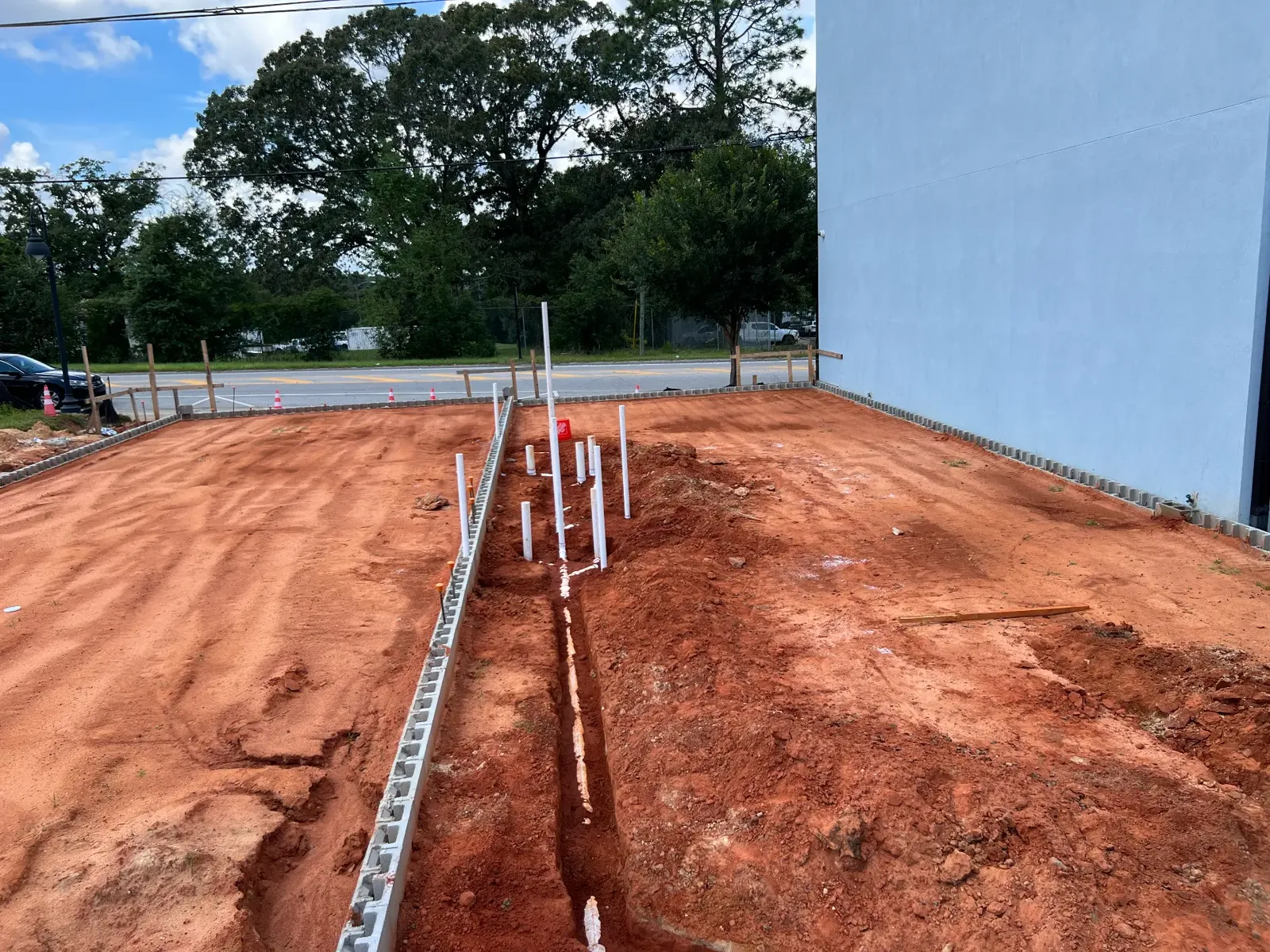 Commercial under-slab plumbing rough-in with PVC stub-outs on a building pad