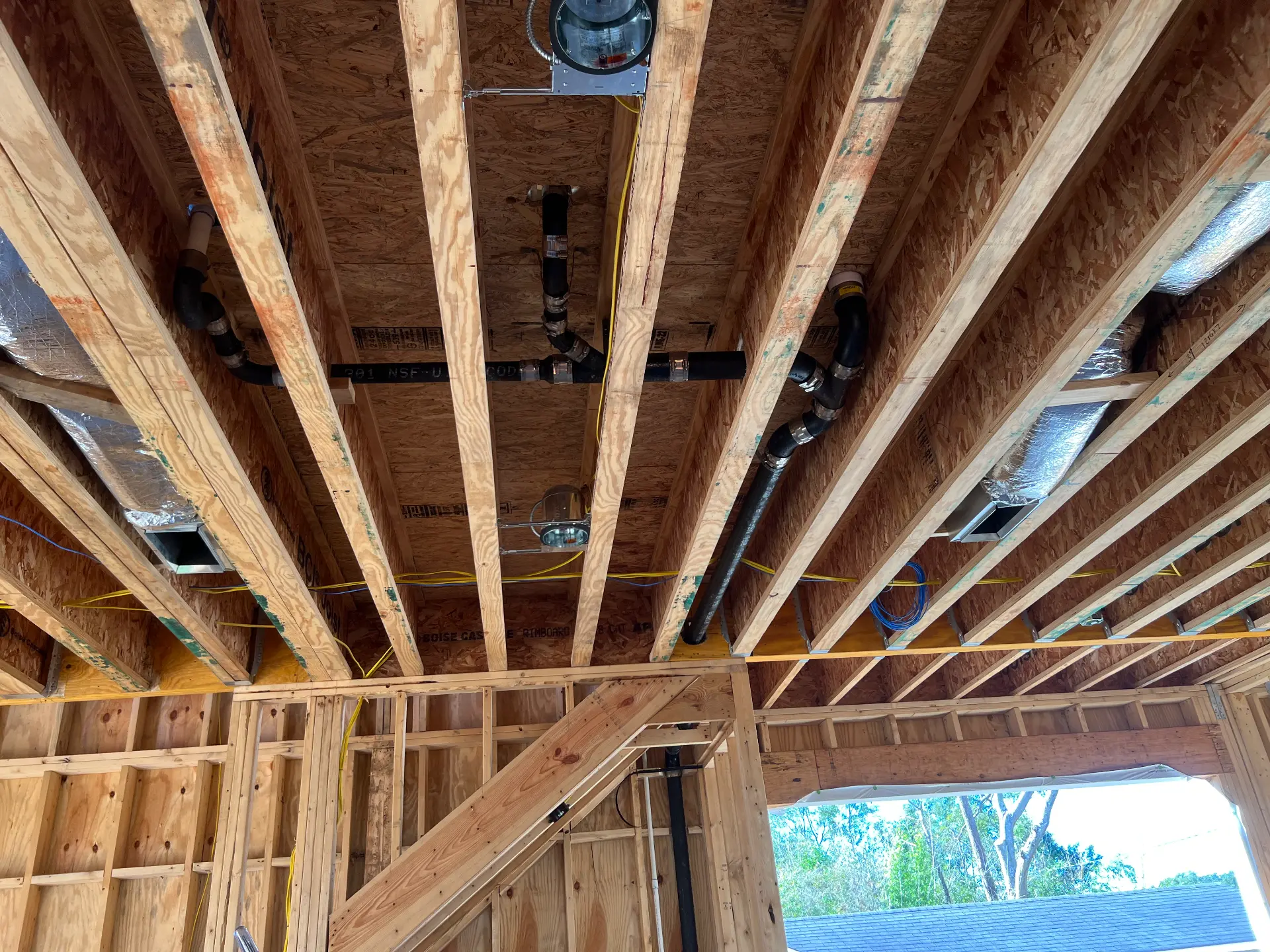 Overhead cast iron drain, waste, and vent piping run through floor joists