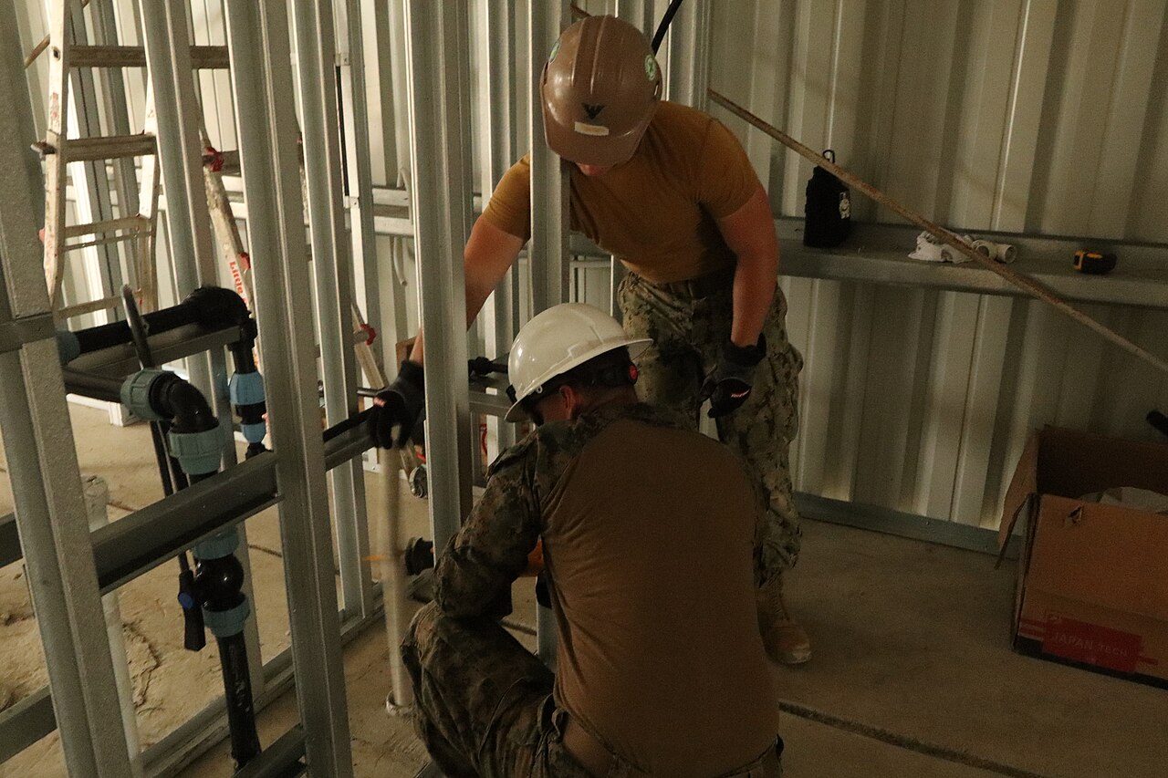 Plumbers installing supply and drain lines in the framed walls of a new building