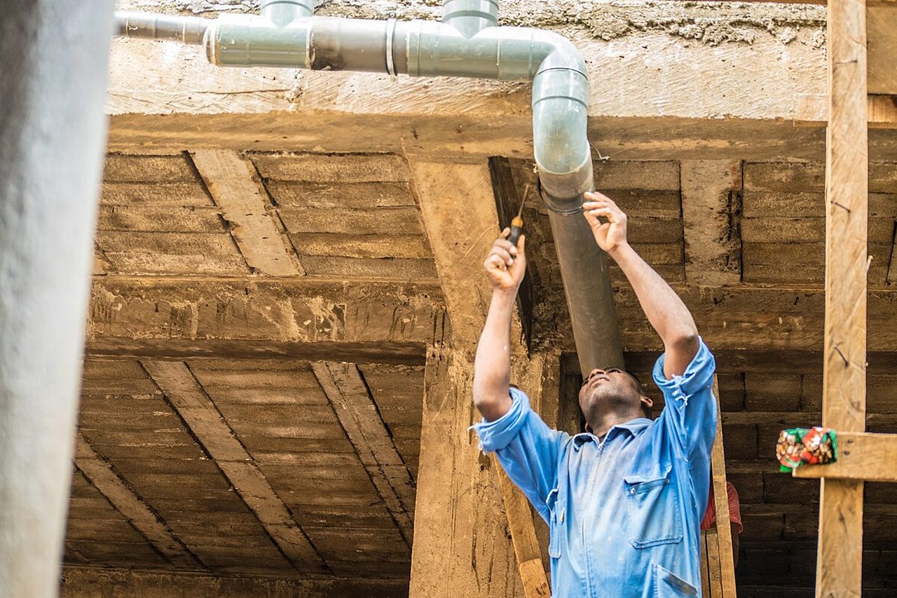 Plumber fitting new pipework overhead during a service job